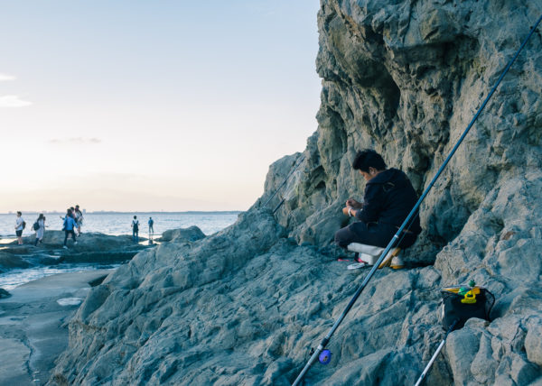 Un pêcheur au creux des rochers se prépare à pêcher dans les aux d'énoshima